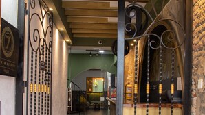 A hotel corridor with a wooden ceiling, a decorative metal gate, and a bar area with a stone wall. - Hostal Seven Nights Cartagena - Hostel (Cartagena)