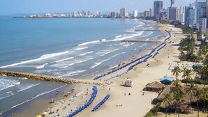 A coastal cityscape with a wide beach, a breakwater, and high-rise buildings in the background. - Hostal Seven Nights Cartagena - Hostel (Cartagena)