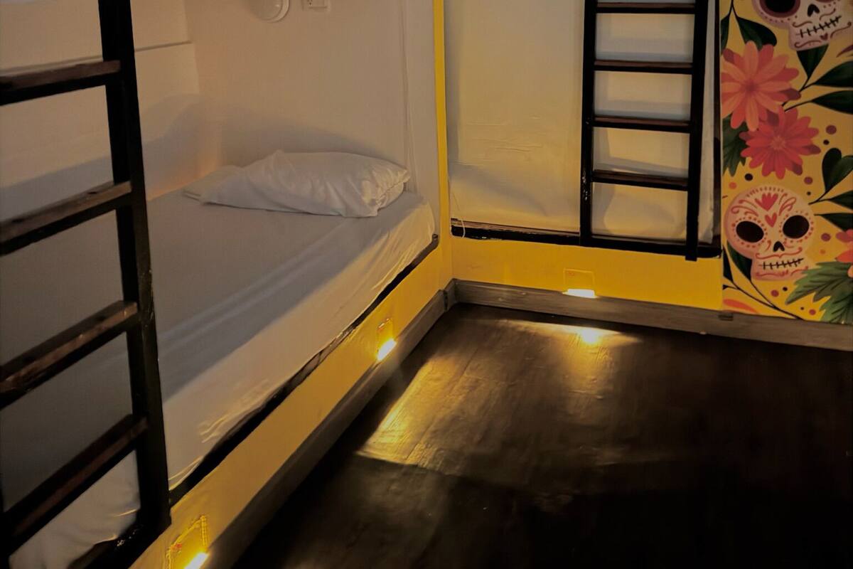 A bunk bed room with a wooden ladder and a small window.