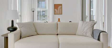 A modern living room with a beige sofa, a floor lamp, and a table with a magazine.