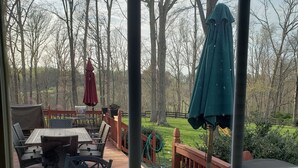 Une terrasse dotée de mobilier d’extérieur, d’un barbecue et offrant une vue sur une zone boisée.