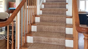 Un escalier avec des rampes en bois et une moquette à motifs.
