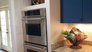 Une cuisine équipée d’appareils électroménagers en acier inoxydable, de meubles bleus et d’un plan de travail en granit.