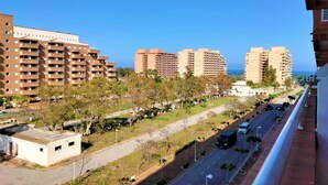 Un edificio residencial alto con varios balcones, un estacionamiento y vista despejada al mar.