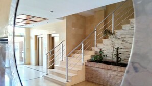 Un interior moderno con una escalera, una pared de ladrillo decorativa y una puerta de cristal que da a otra habitación.