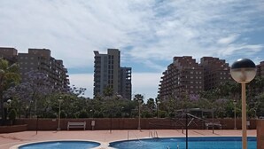 Zona de piscina en la azotea con dos piscinas, rodeada de edificios altos y árboles.