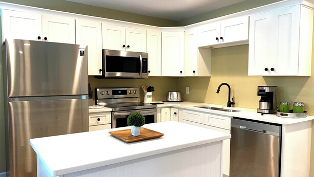 Una cocina moderna con armarios blancos, electrodomésticos de acero inoxidable y una isla central.