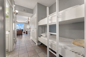 A bunk bed room with a hallway leading to a kitchen and living area.