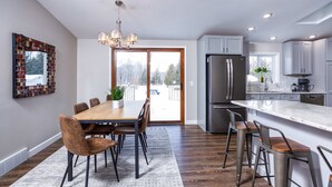 A modern kitchen with a large island, stainless steel appliances, and a dining area with a wooden table and chairs. - The Reserve at Plum Bottom in Egg Harbor! (Egg Harbor)