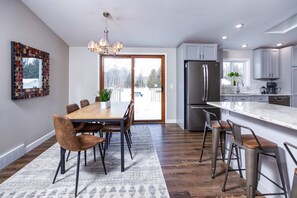 A modern kitchen with a large island, stainless steel appliances, and a dining area with a wooden table and chairs.