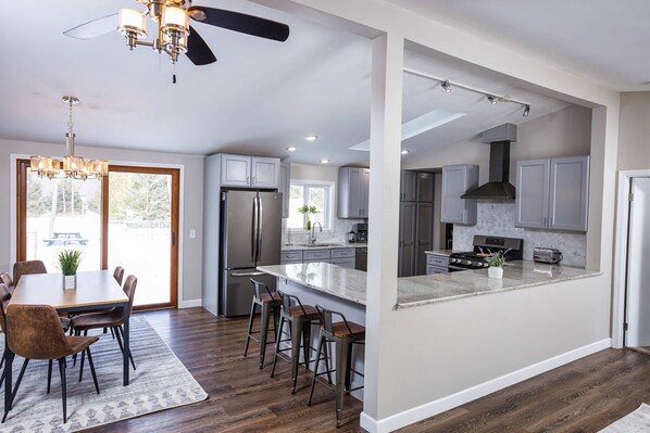 A modern kitchen with a central island, stainless steel appliances, and a dining area with a chandelier.