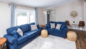 A modern living room with two blue sofas, a round coffee table, and a small side table. - The Reserve at Plum Bottom in Egg Harbor! (Egg Harbor)