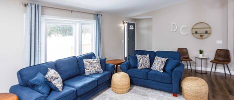 Ein modernes Wohnzimmer mit zwei blauen Sofas, einem runden Couchtisch und einem kleinen Beistelltisch.