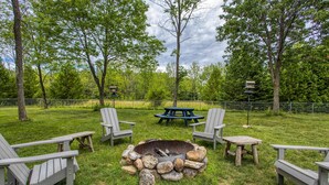 A backyard with a fire pit, picnic table, and Adirondack chairs. - The Reserve at Plum Bottom in Egg Harbor! (Egg Harbor)