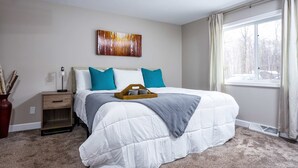 A bedroom with a large bed, a bedside table, a wall-mounted artwork, and a window with curtains. - The Reserve at Plum Bottom in Egg Harbor! (Egg Harbor)