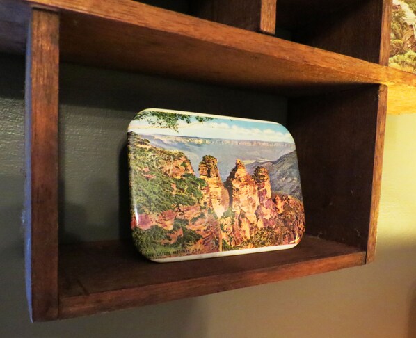 A wooden shelf with a decorative item featuring a landscape painting.