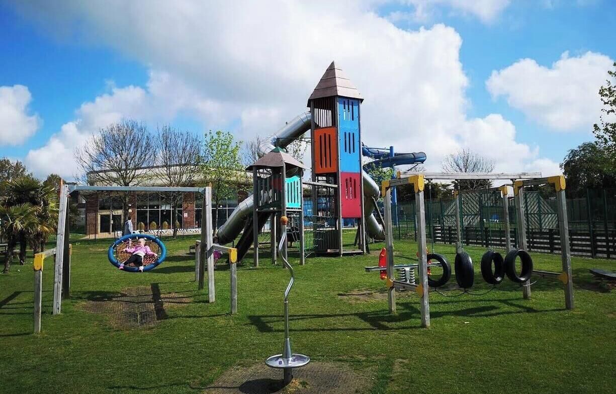 Un parque infantil con tobogán, estructuras para escalar y columpios.