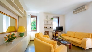 A living room with yellow furniture, a TV, and a dining area with a table and chairs. - Appartamento Gaya 2BR with Terrace, Stresa, Italy (Stresa)
