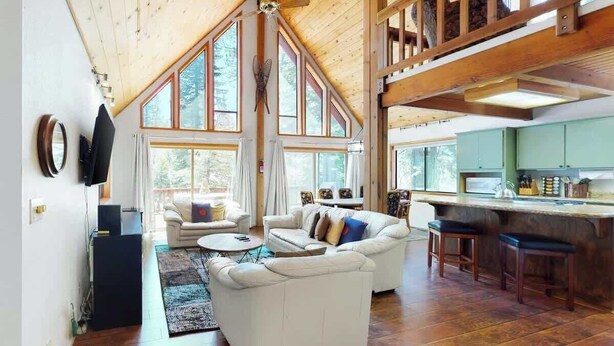 Un salón amplio con techo alto, ventanas grandes y detalles de madera.