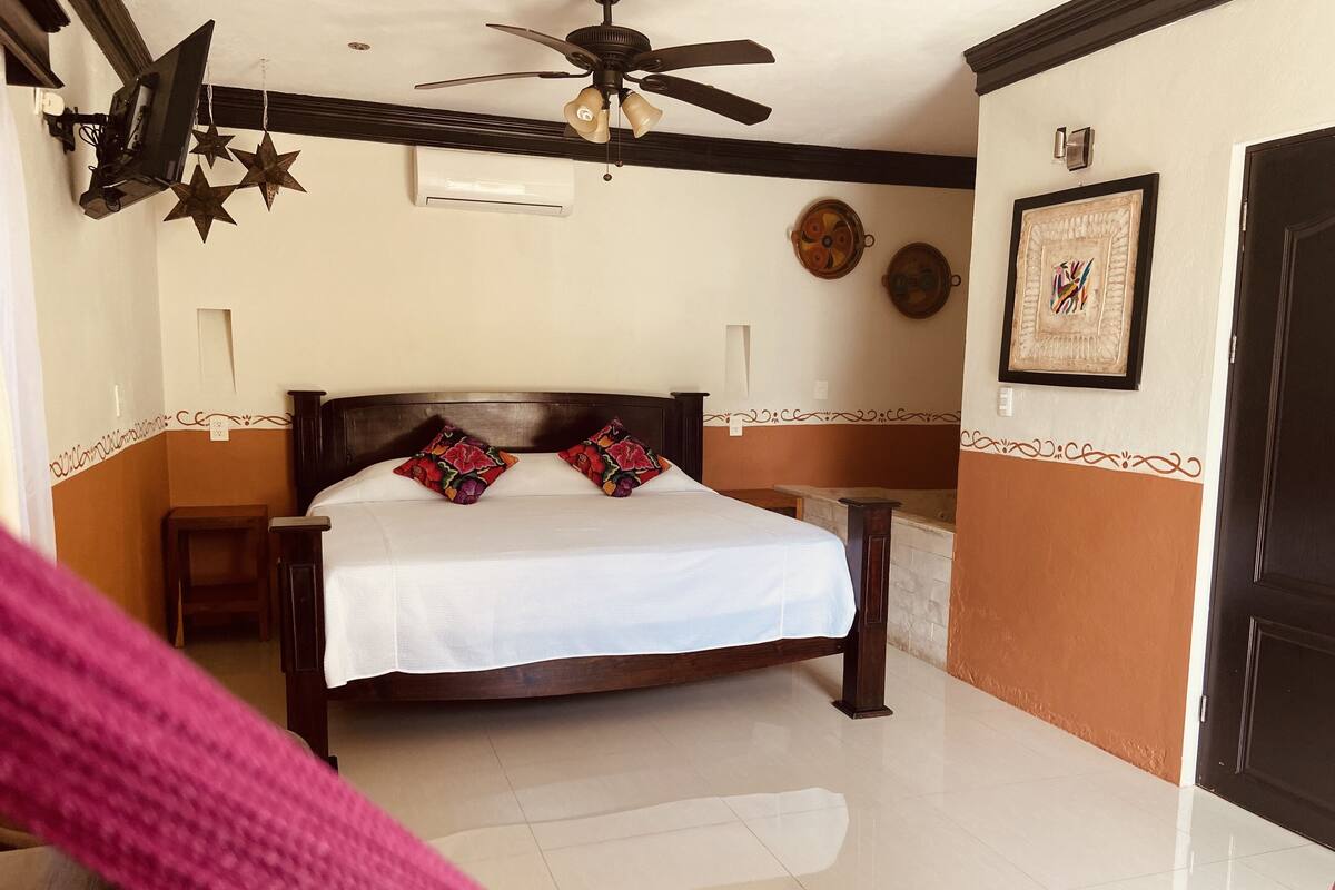 A bedroom with a bed, a ceiling fan, decorative wall art, and a door.