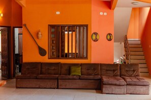 Un salon avec un ensemble de meubles marron, une porte en bois et un escalier.