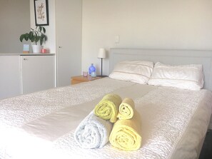 Relax in a serene space with a comfortable bed, a nightstand, and a potted plant.