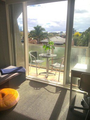 Enjoy the city view from this balcony with a table, chairs, and a bench.