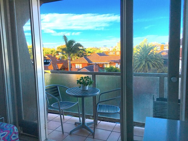 Relax on the balcony with a view of the serene residential area, featuring a table and two chairs.