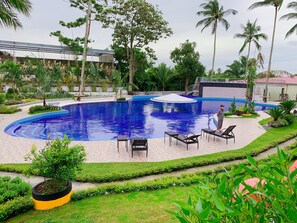 A swimming pool with a circular design, surrounded by a well-maintained garden and palm trees. - Starview Hotel and Resort (Silang)