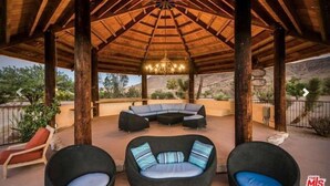 Un espace extérieur abrité, doté d’un toit de chaume, d’un canapé intégré et de deux fauteuils.