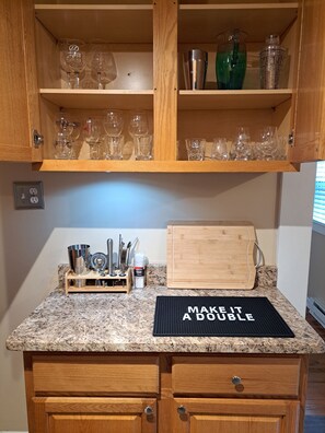 Eine Küche mit Holzausstattung, einer Granit Arbeitsplatte, einem Schneidebrett und einer Matte mit Aufdruck.