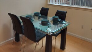 A dining area with a glass table, black chairs, and a painting on the wall. - Comfy 2 bdrm 1 bath 3 beds in-law unit w/kitchen (Daly City)