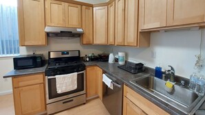 A modern kitchen with wooden cabinets, a stainless steel sink, a microwave, an oven, and a gas stove. - Comfy 2 bdrm 1 bath 3 beds in-law unit w/kitchen (Daly City)