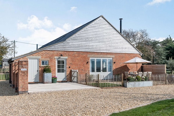 Guests can enjoy a peaceful retreat in this charming single-story building with a seating area and easy access to the surrounding lawn and trees.