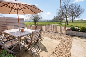 Relax on the patio surrounded by a serene countryside landscape.