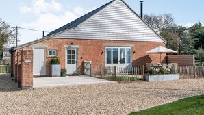 A brick building with a white door, windows, and a gravel driveway.