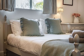 Classic design bedroom with a central bed, crisp bedding, and a bedside table.