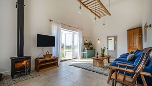 A living room with a fireplace, a sofa, a TV, and a wooden ceiling structure.