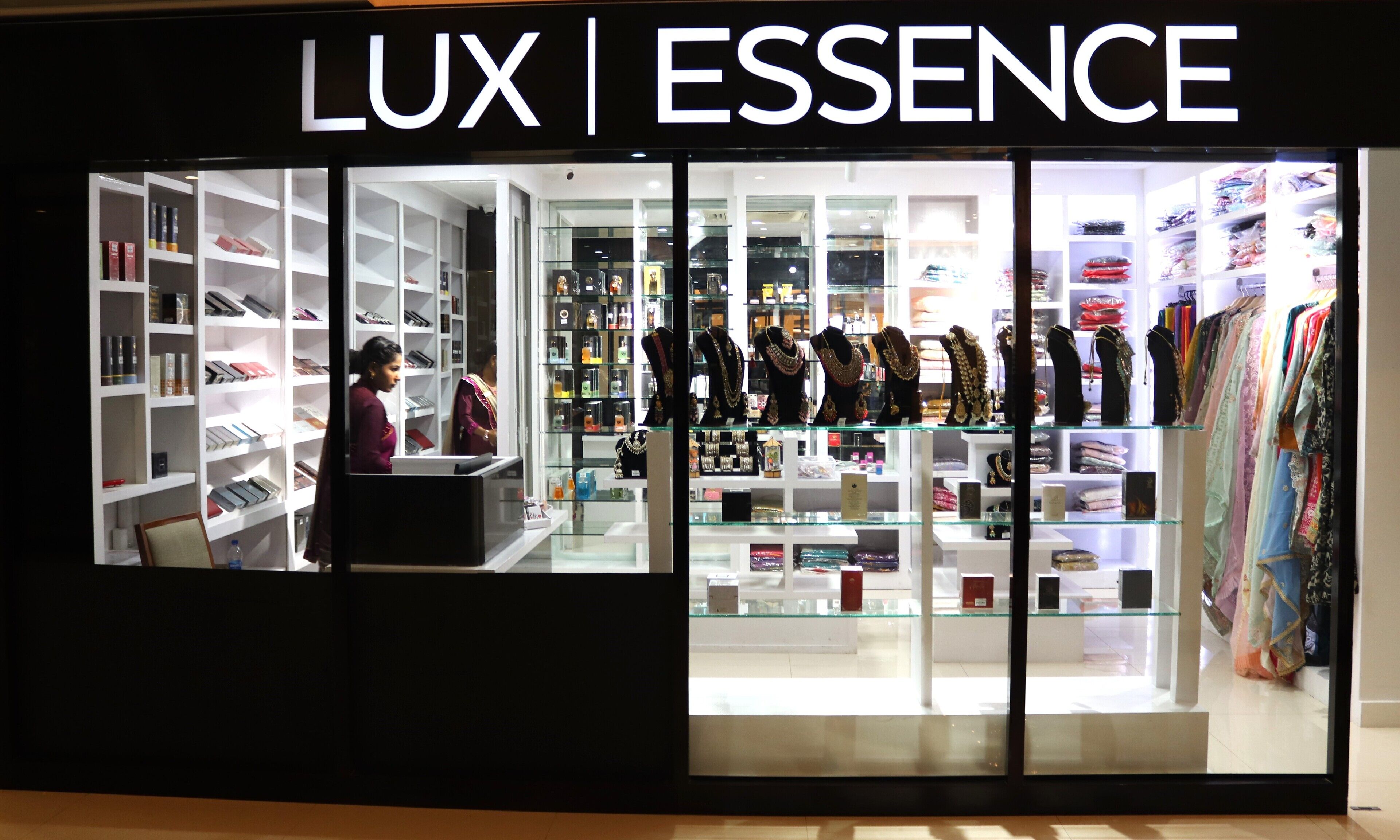 Une boutique appelée « LUX | ESSENCE » où l’on trouve des bijoux et des vêtements exposés sur des étagères.