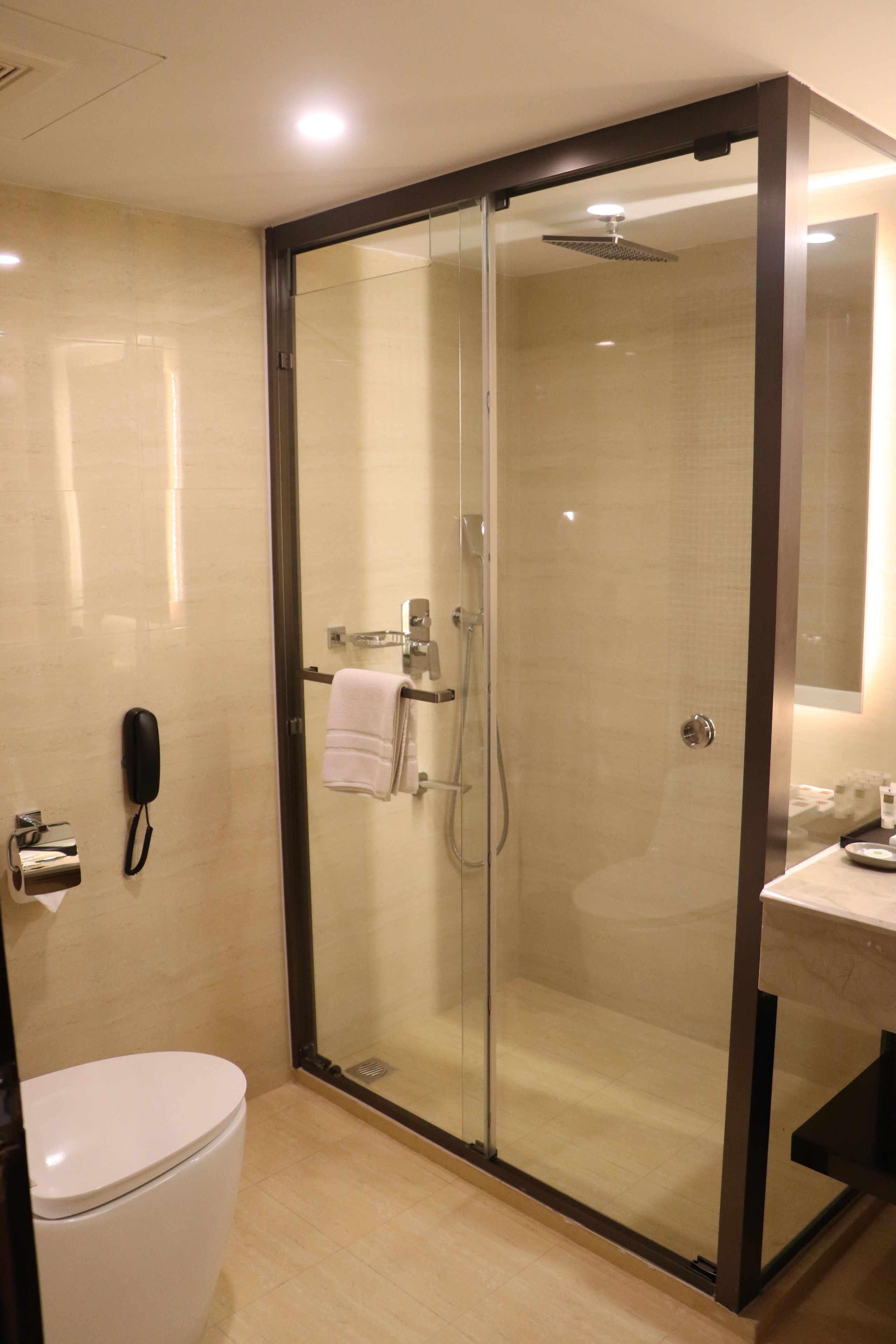 Une salle de bain moderne avec une douche à parois de verre, des toilettes et un lavabo avec un miroir.