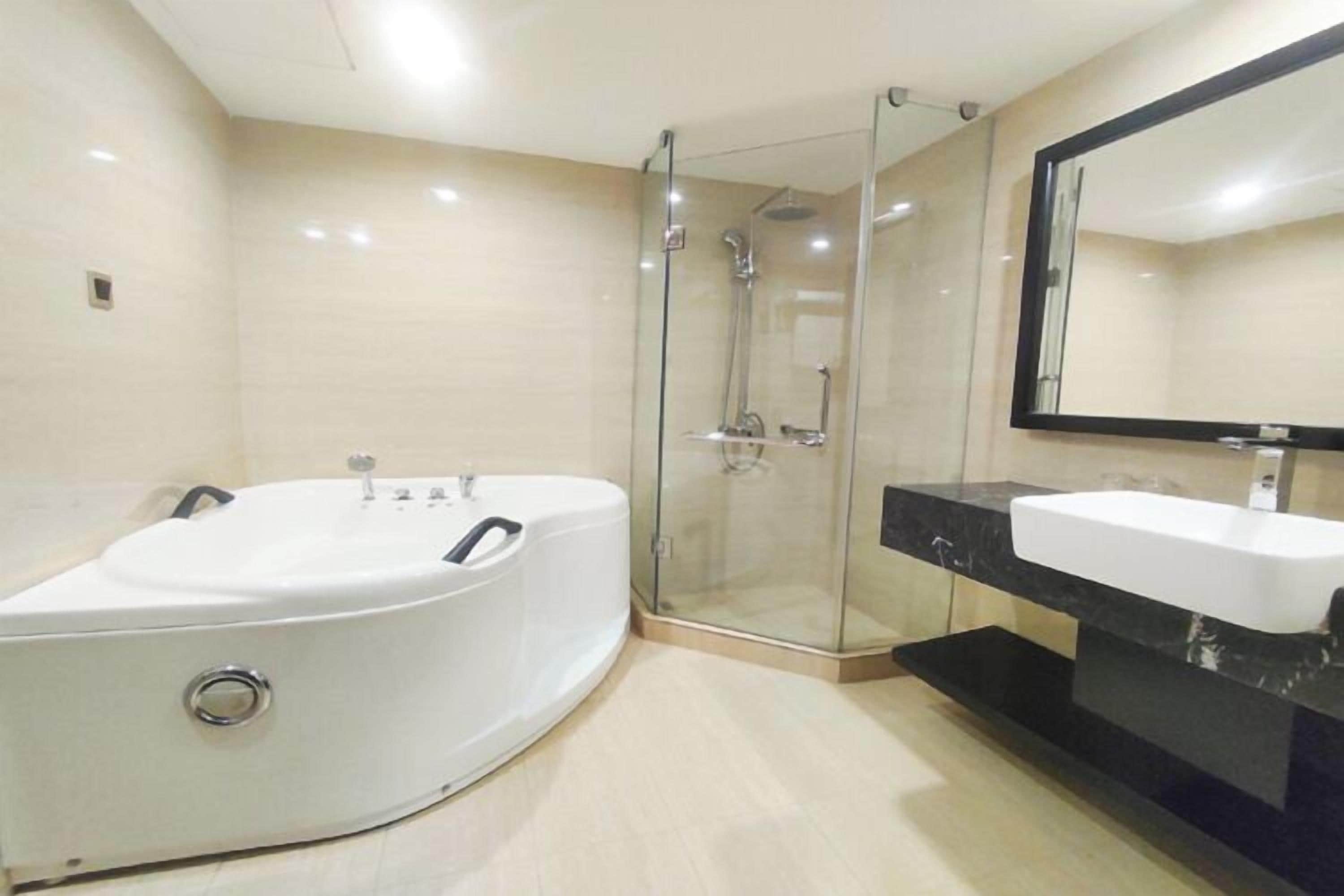 A modern bathroom with a large bathtub, a glass-enclosed shower, and a vanity with a mirror.