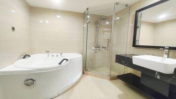 A modern bathroom with a large bathtub, a glass-enclosed shower, and a vanity with a mirror.