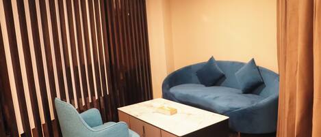 A modern living room with a blue sofa, a light blue armchair, and a marble coffee table.