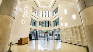 Un hall d’entrée spacieux avec un plafond haut, un lustre central et un comptoir de réception.