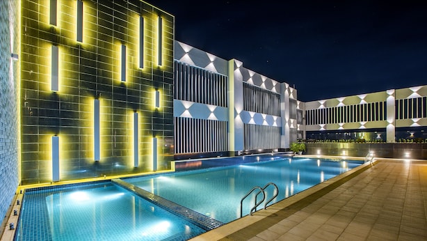 Une piscine située à côté d’un bâtiment aux motifs géométriques et doté d’un éclairage moderne.