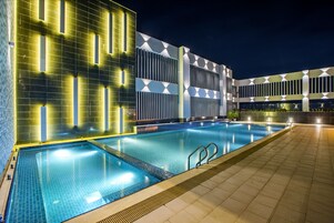 Una piscina al aire libre, sombrillas, sillones reclinables de piscina