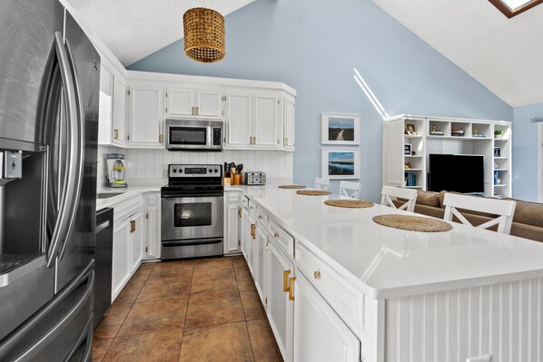 A modern kitchen with white cabinetry, stainless steel appliances, and a large island with seating. - Impeccable 3-bedroom, private pool, sunroom, marsh views - Cherry Grove Beach (North Myrtle Beach)