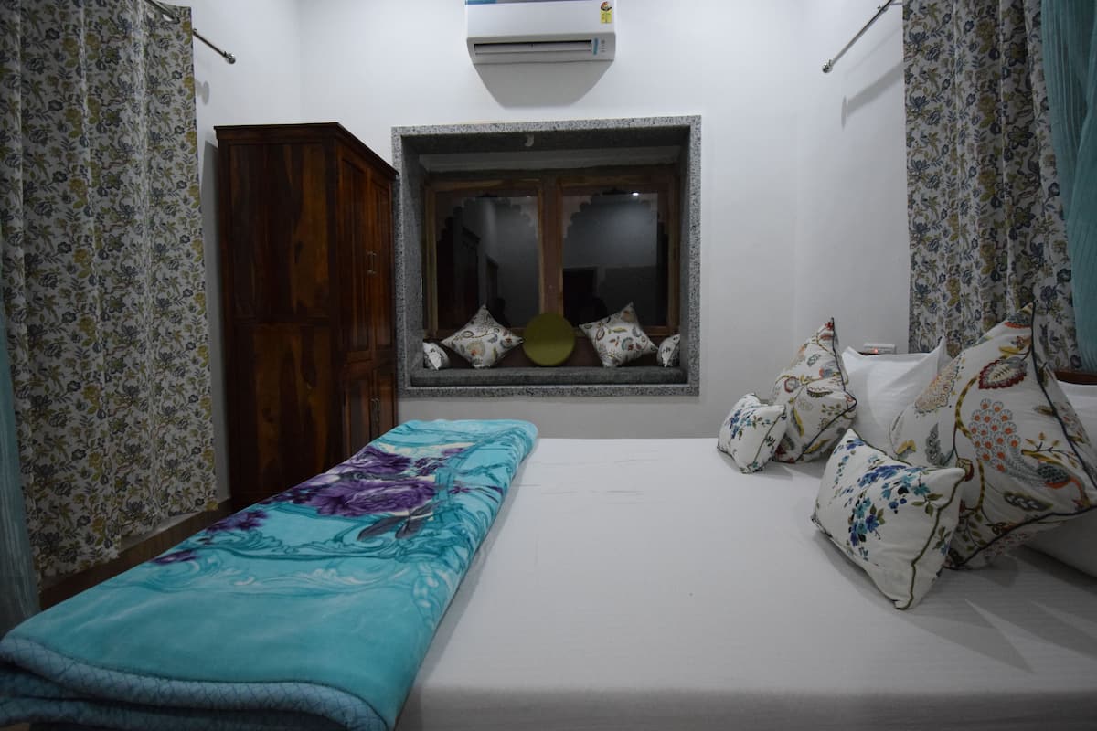 Un dormitorio con cama, ventana con vistas, armario y cortina.