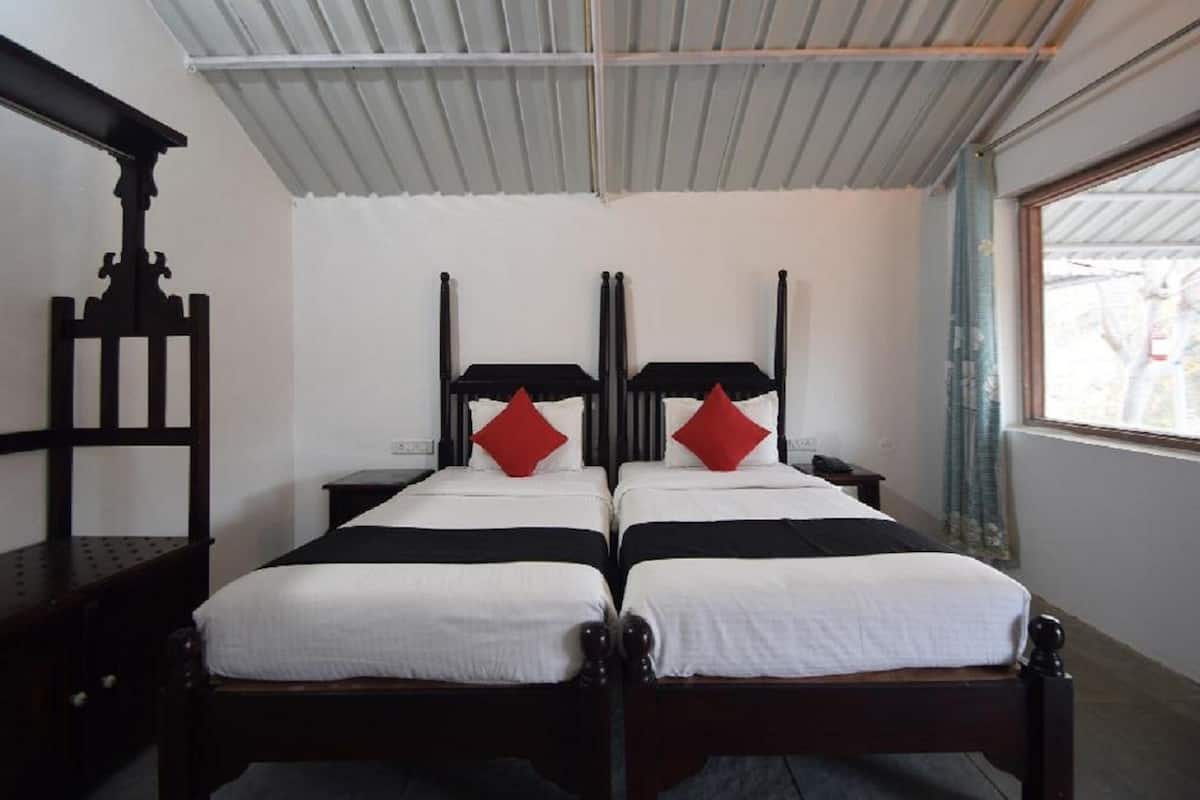 Cama doble con cabeceros negros y almohadas rojas, una mesita de noche de madera y una ventana con vistas.