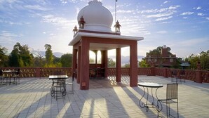 Ein Pavillon mit Kuppel und Laternen, umgeben von Sitzmöbeln im Freien und einer gefliesten Terrasse.